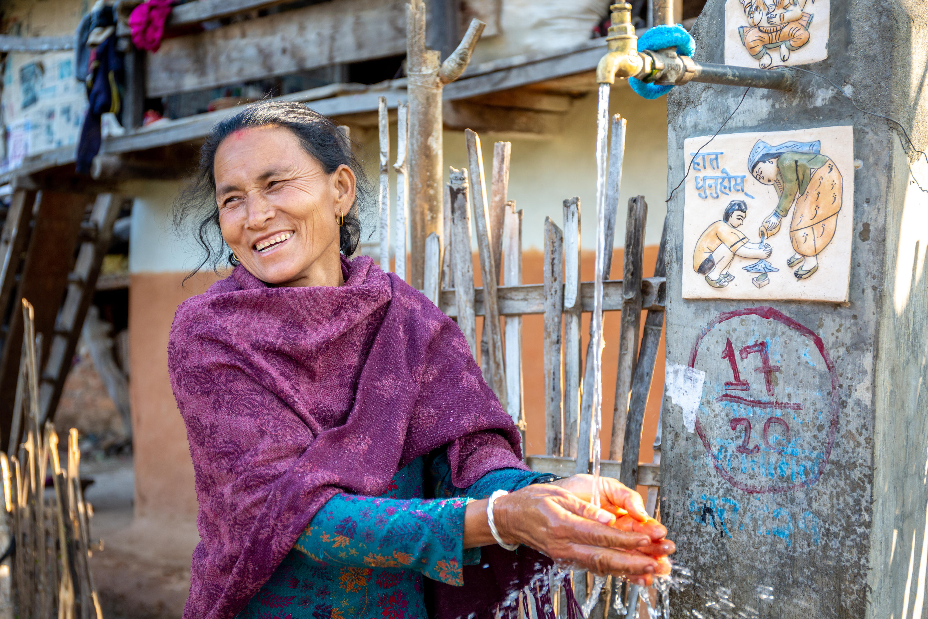 Kumari Maya Shrestha a lavar as mãos na torneira perto de sua casa em Mayankhu, Nepal.