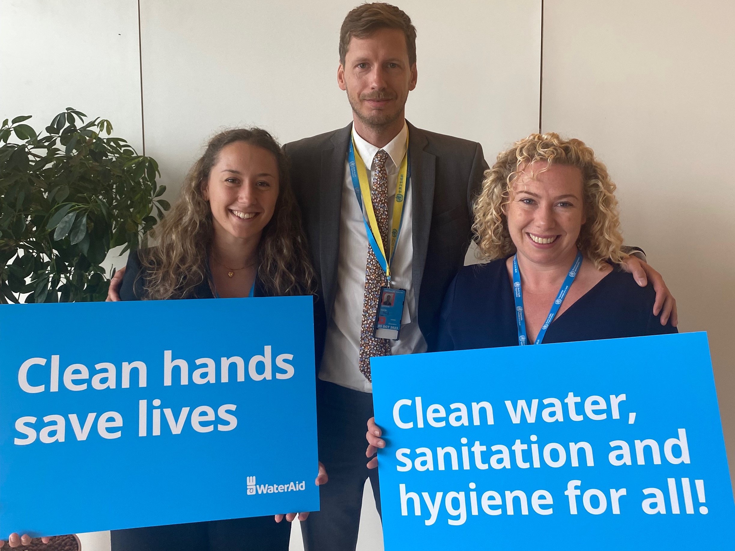 Members of Sweden's delegation to the World Health Assembly and WaterAid's Helen Hamilton hold placards saying 'clean hands save lives' and 'clean water and sanitation for all!'at the 75th World Health Assembly 2022.