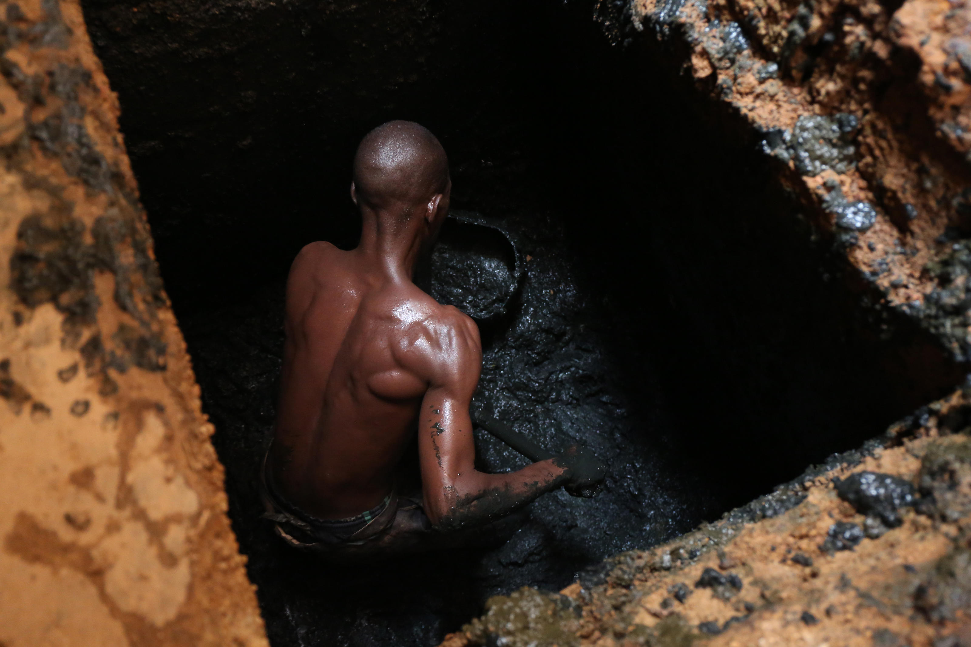 Paul Zongo, esvaziador manual, dentro de um poço, a esvaziar uma latrina familiar em Ouagadougou, Burkina Faso.