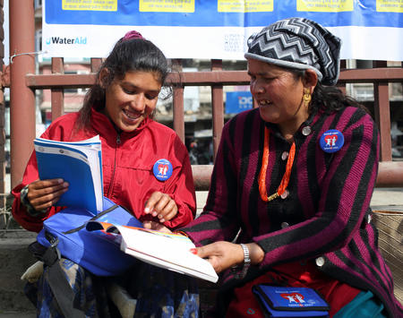 Kanchhi e a filha Meena, a estudar ferramentas usadas no projeto Eliminar barreiras menstruais, fora do escritório de Banepa Muncipality, Kavre, Nepal.